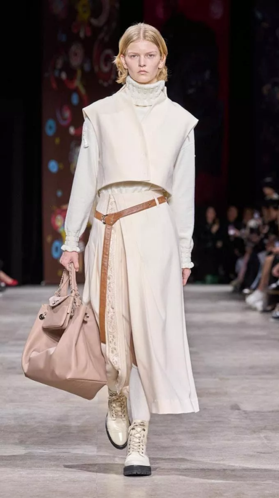 Modella che indossa stivali bianchi al ginocchio, abbinati a un outfit invernale elegante e sofisticato.