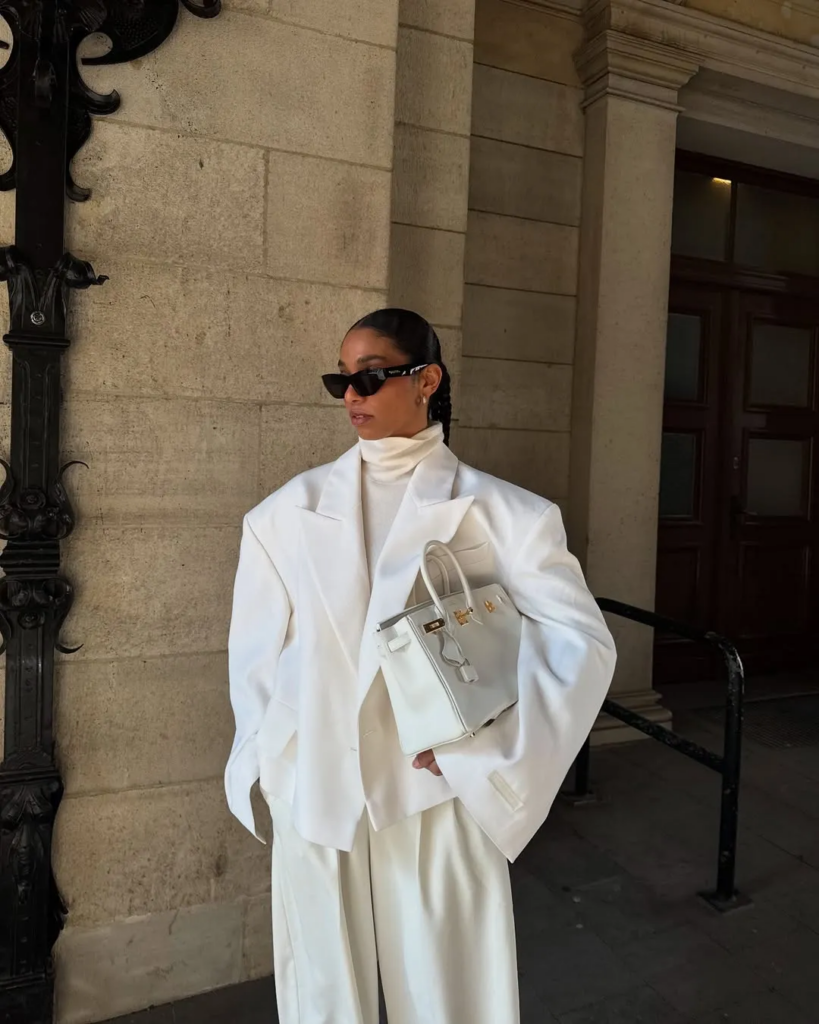 Donna elegante in outfit bianco invernale, abbigliamento tono su tono con giacca e pantaloni bianchi, look chic e sofisticato.
