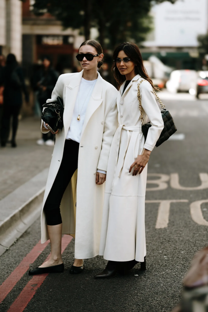 Due donne che camminano indossando cappotti bianchi in inverno, outfit eleganti e coordinati.
