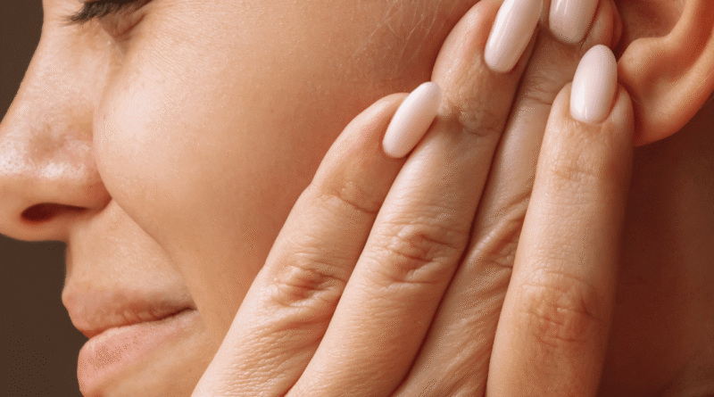 Donna che si tocca un orecchio con espressione di dolore, possibile fastidio o infezione all’orecchio