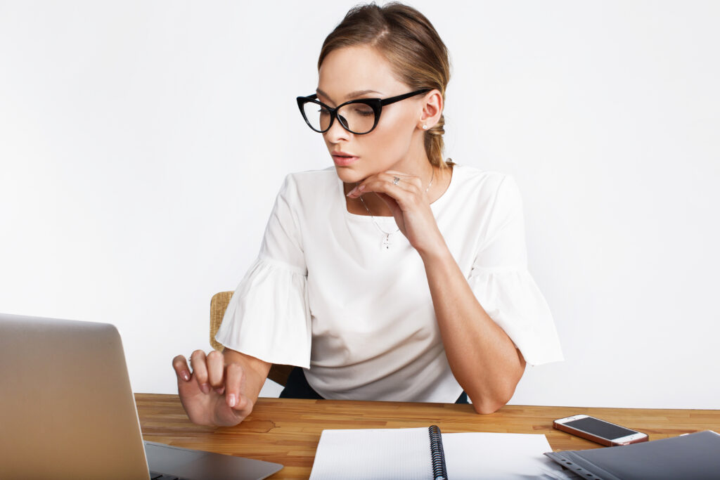 Donna seduta al computer, pensierosa mentre lavora, ambiente luminoso e ordinato.