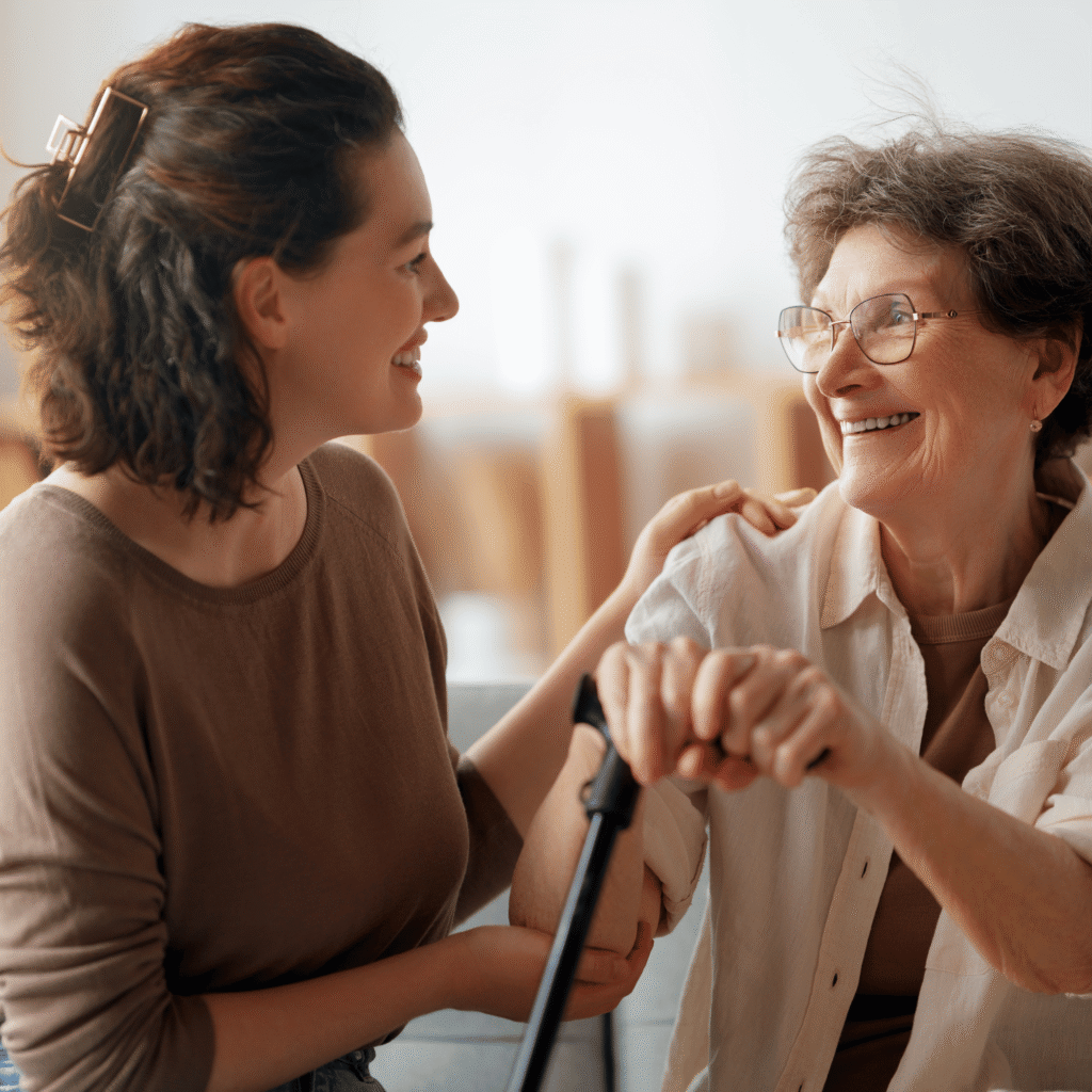 Caregiver donna che sorride mentre aiuta un’anziana signora a sentirsi a suo agio