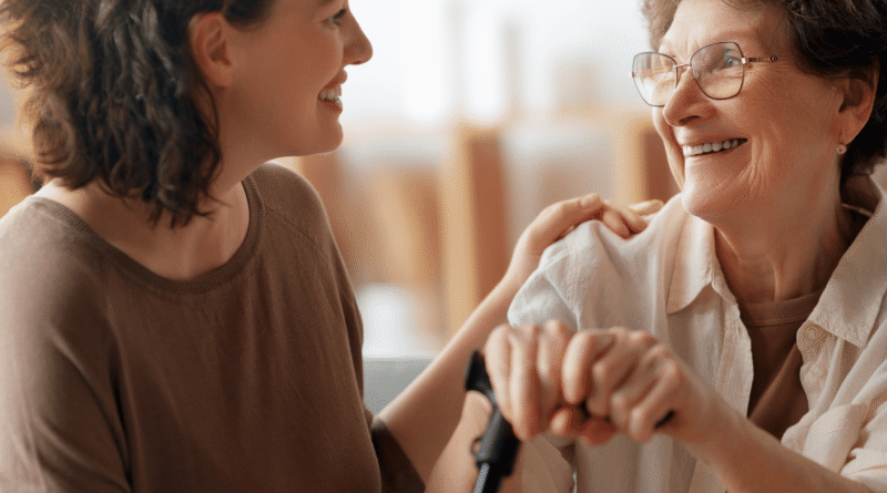 Caregiver donna che sorride mentre aiuta un’anziana signora a sentirsi a suo agio
