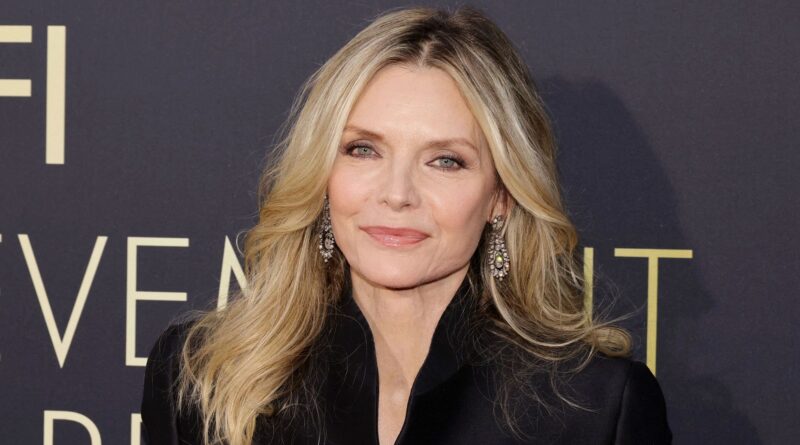 Michelle Pfeiffer sorride e posa sul red carpet durante un evento di gala, indossando un elegante abito da sera