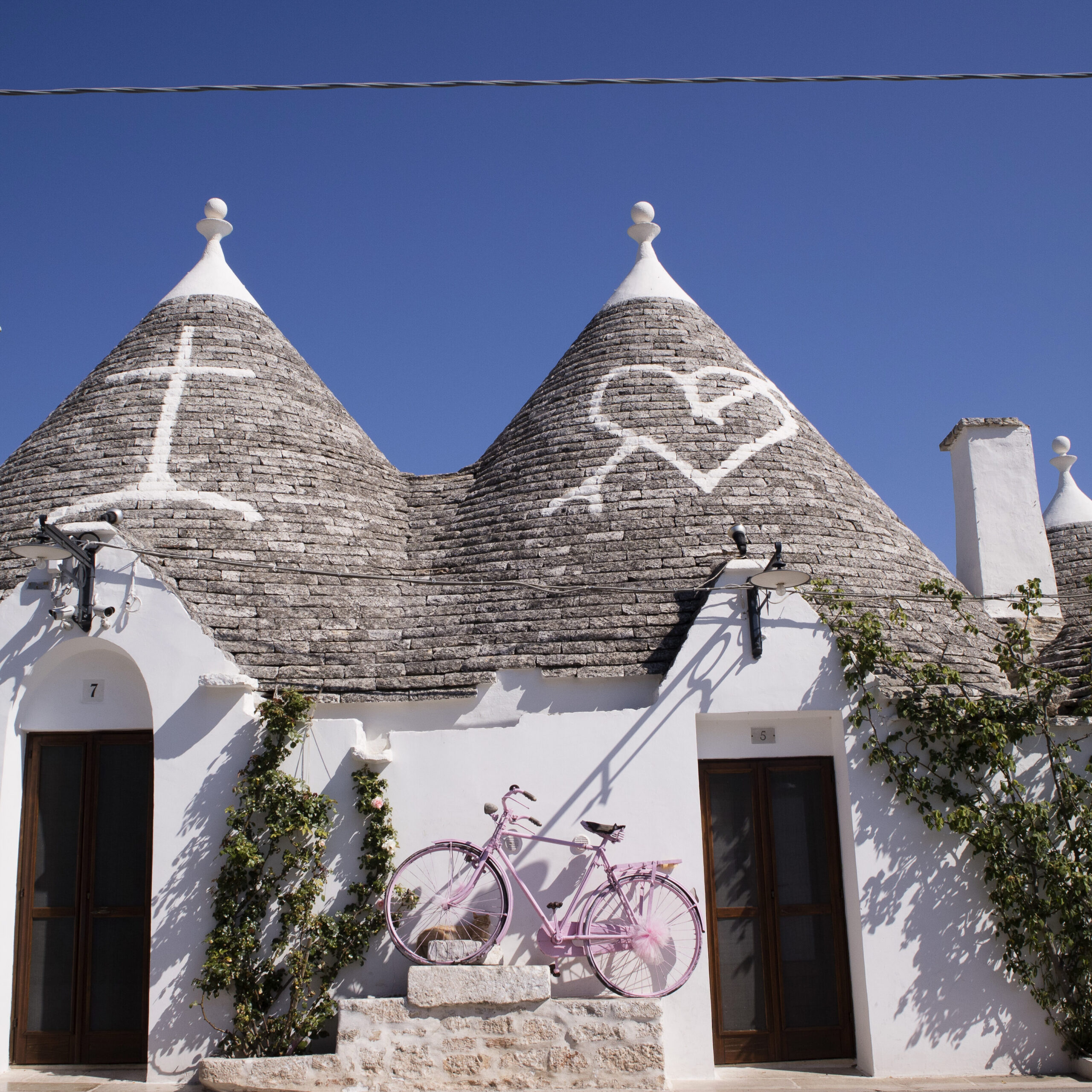 Trulli tradizionali in pietra bianca ad Alberobello in Puglia, con tetti conici sotto cielo azzurro