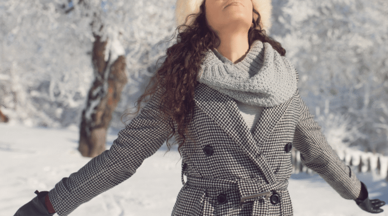 Donna rilassata sulla neve in abbigliamento invernale, godendosi la montagna e il paesaggio innevato