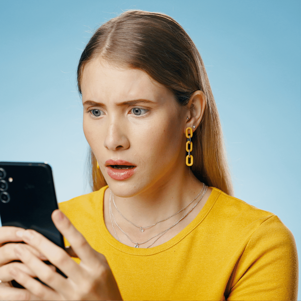 Donna adulta che guarda il proprio smartphone con espressione scioccata